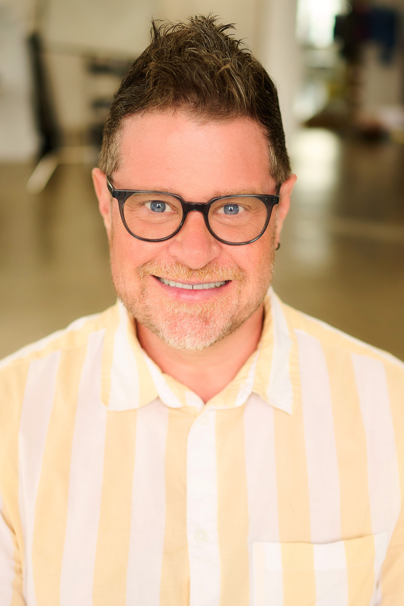 This is a head shot of Craig Thomas, real estate agent in Los Angeles Ca. wearing his glasses and a yellow stripped shirt.